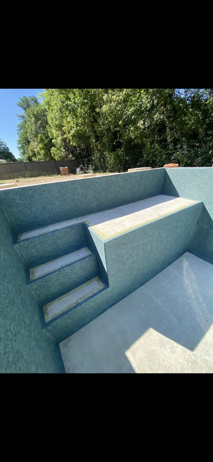 Bassin vide avec revêtement bleu, escalier et grande banquette.